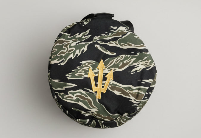 camouflage-patterned bag with a logo on a wooden floor.