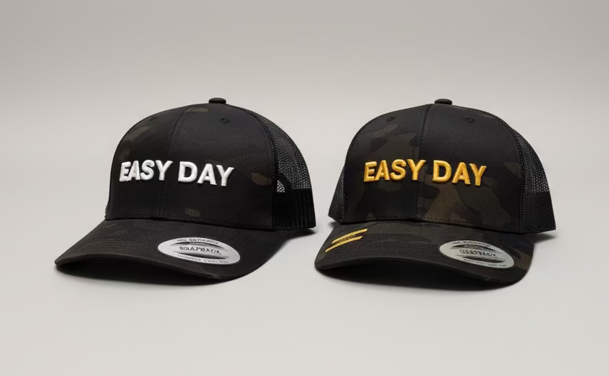 Two black caps with 'Easy DAY' text on a white surface in a room.