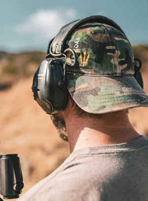 EASY DAY® camo hat with gold trident logo on range day, worn with ear pro