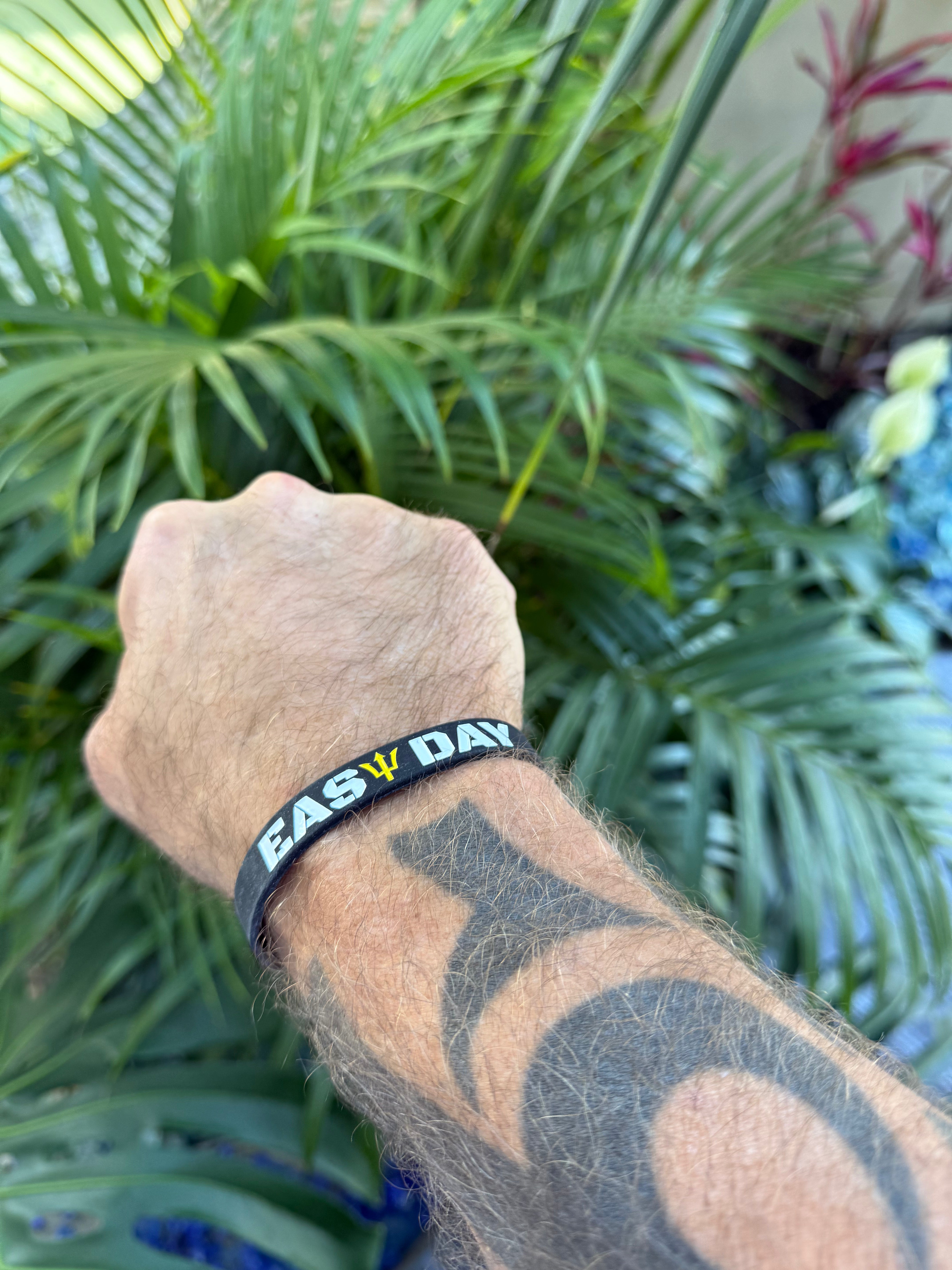 Person wearing a Easy Day wristband with text in front of green plants