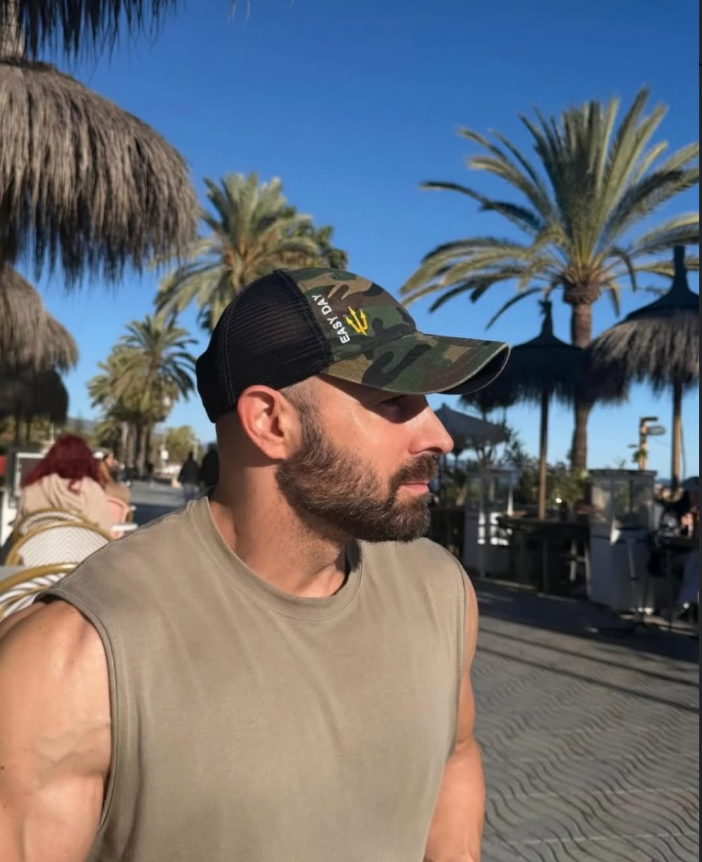 Man wearing a easy day camo cap with palm trees in the background