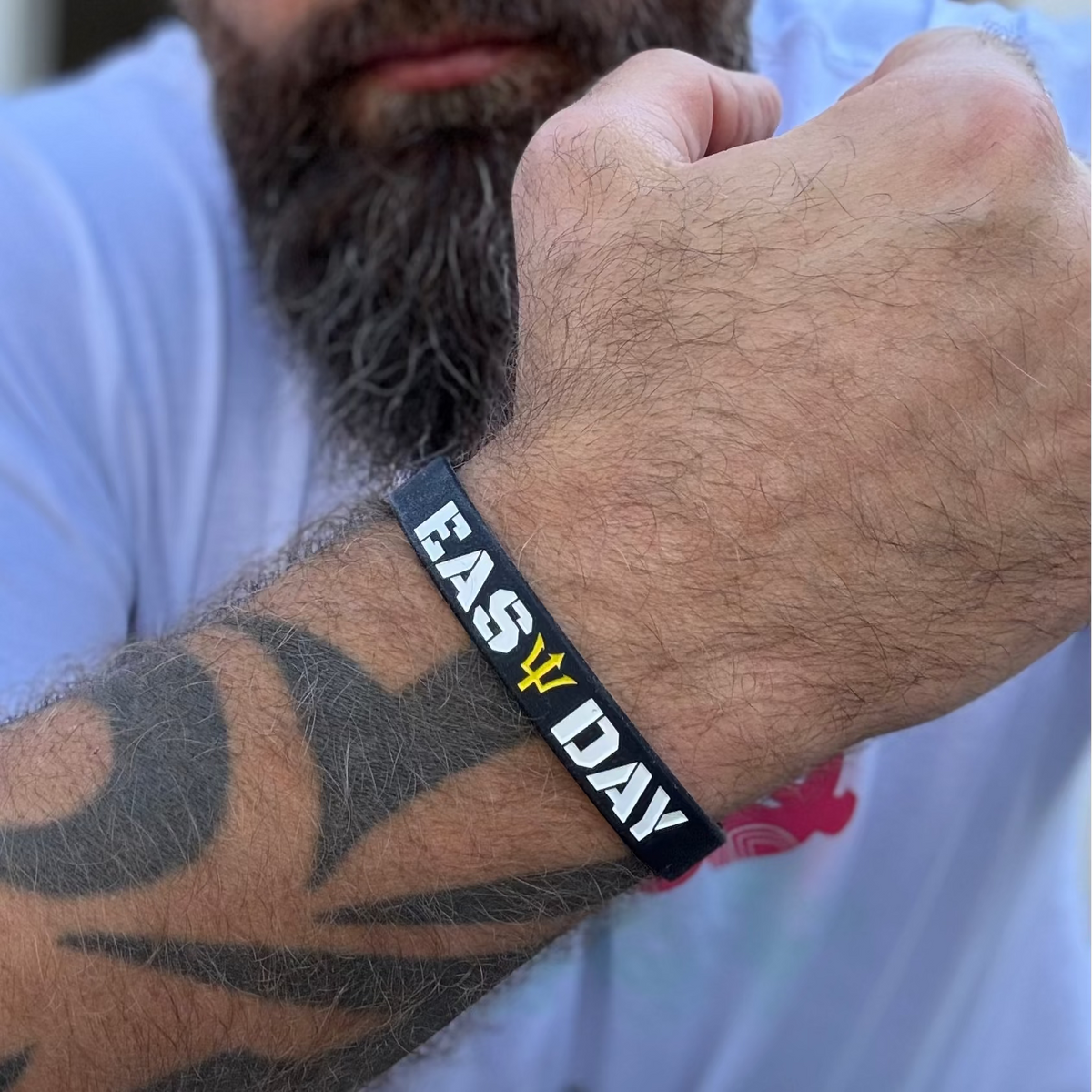 Man wearing a black wristband with 'EASY DAY' text on his arm.